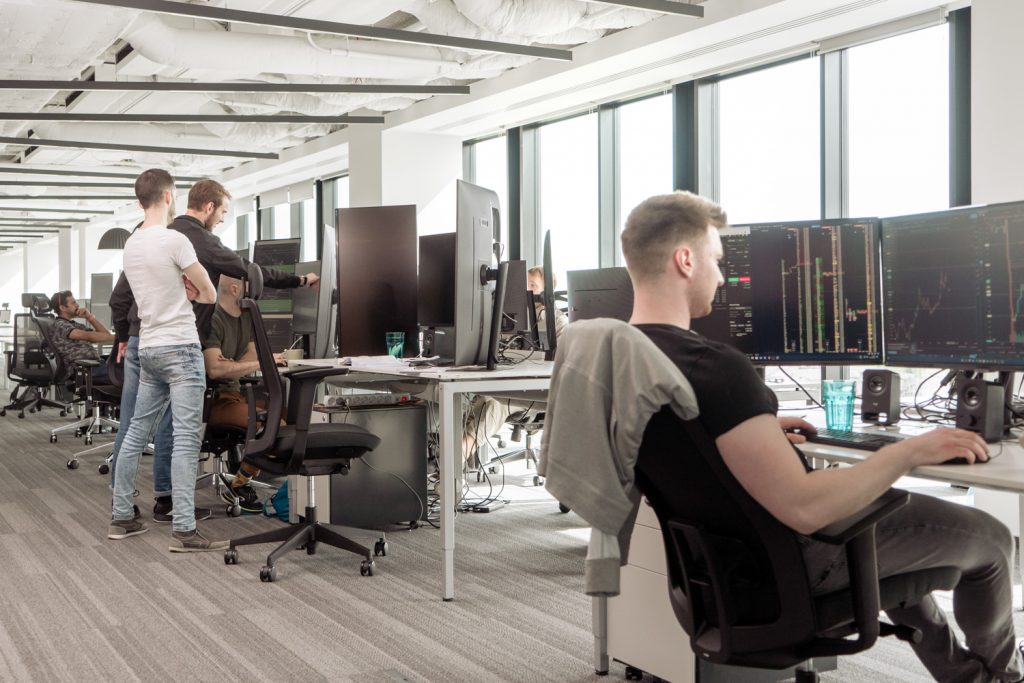 Traders talking and working at their desks in the new WOO Network office.
