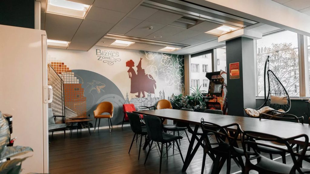 Spacious area within the Biznes Zone Workspace featuring a mural, tables and chairs